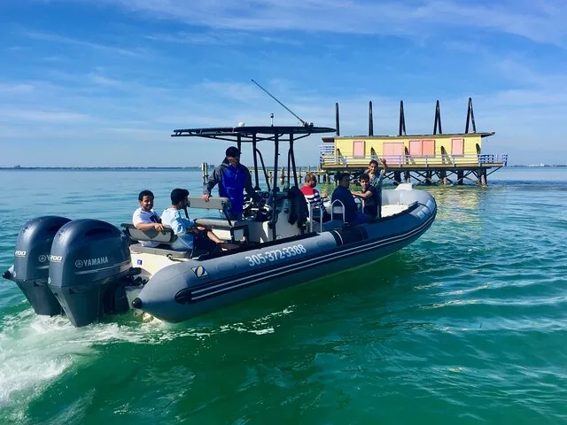 Passagers à bord d’un canot pneumatique à coque rigide passant devant les maisons de Stiltsville à Miami
